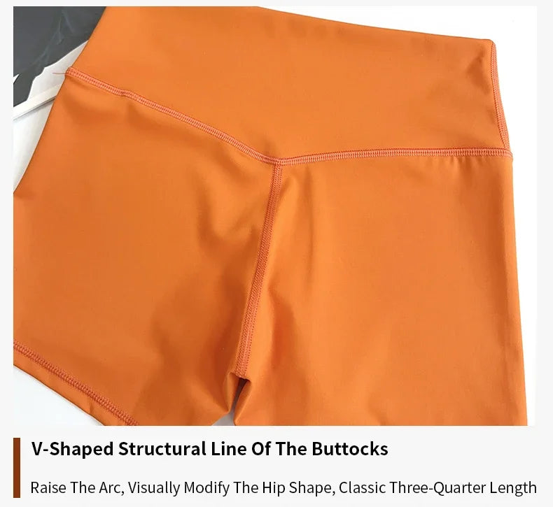 Orange athletic shorts with a V-shaped structural line on a white background