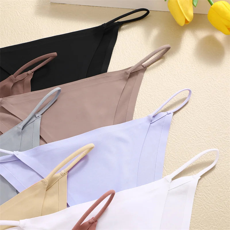 Set of various colored bras on a light surface with yellow flowers in the corner.