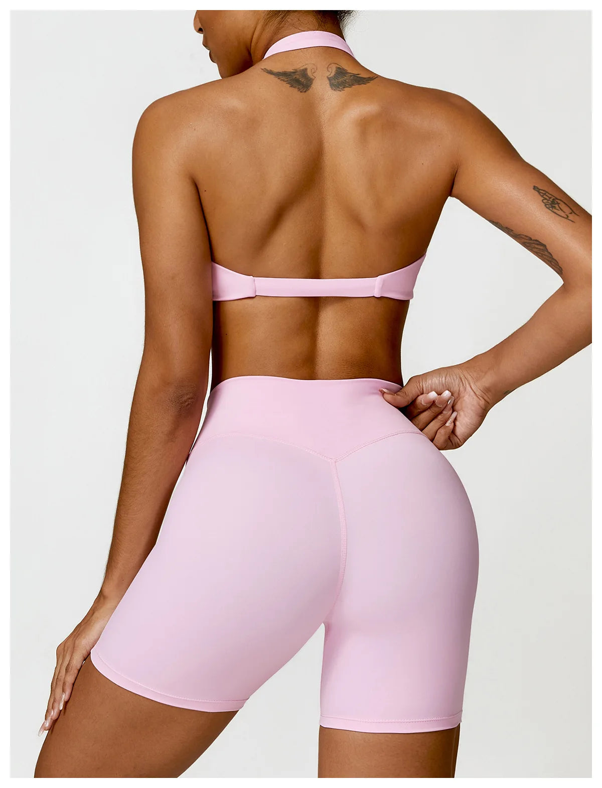 Person wearing a pink sports bra and shorts on a white background