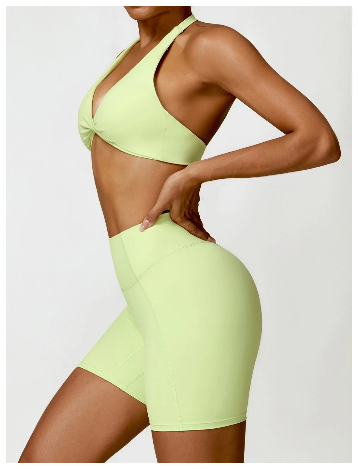 Person wearing a light green sports bra and shorts set on a plain background