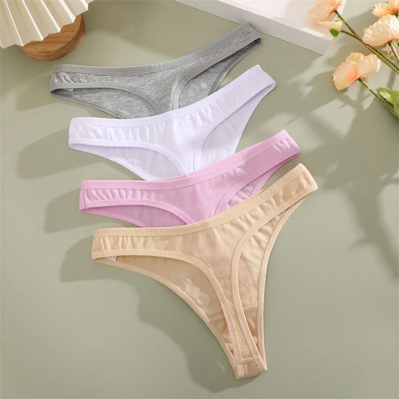 Four pairs of women's underwear in different colors on a light green surface.