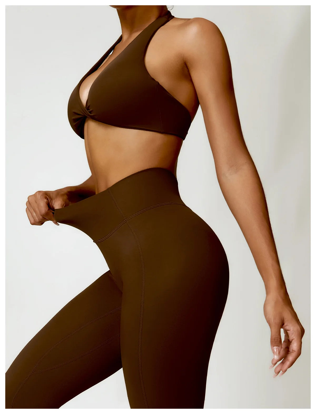 Person wearing a brown sports bra and leggings on a plain background