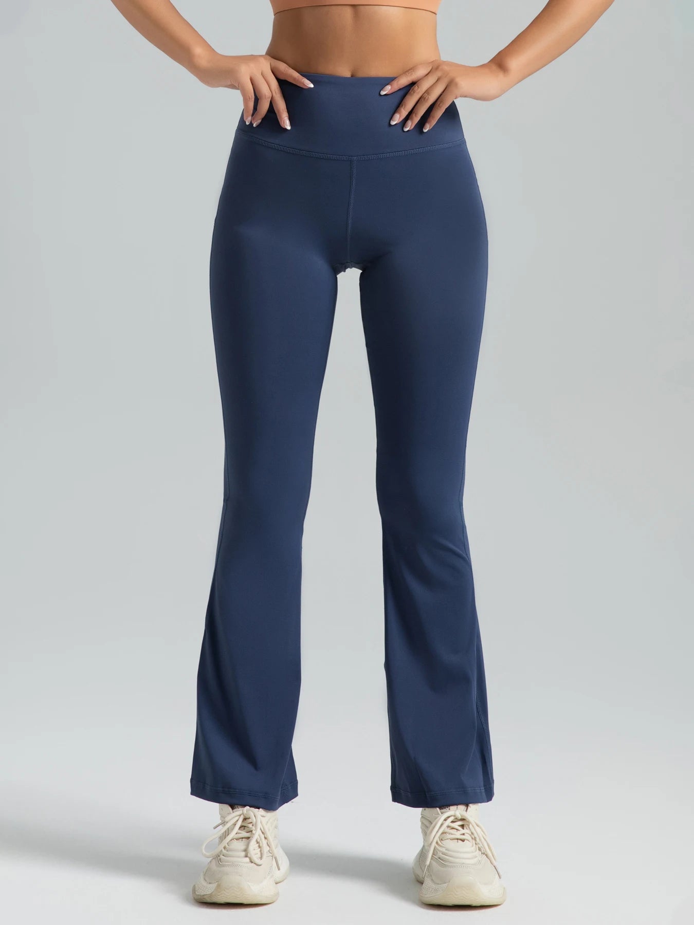 Person wearing navy blue flared pants on a light gray background