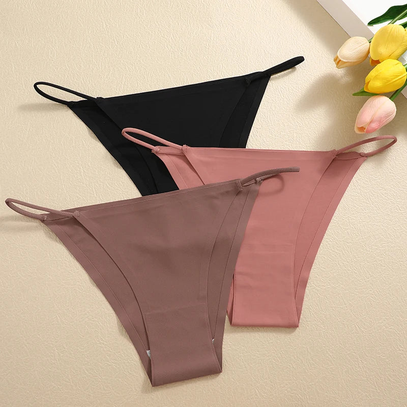 Black and pink bikini bottoms on a beige surface with flowers in the corner.