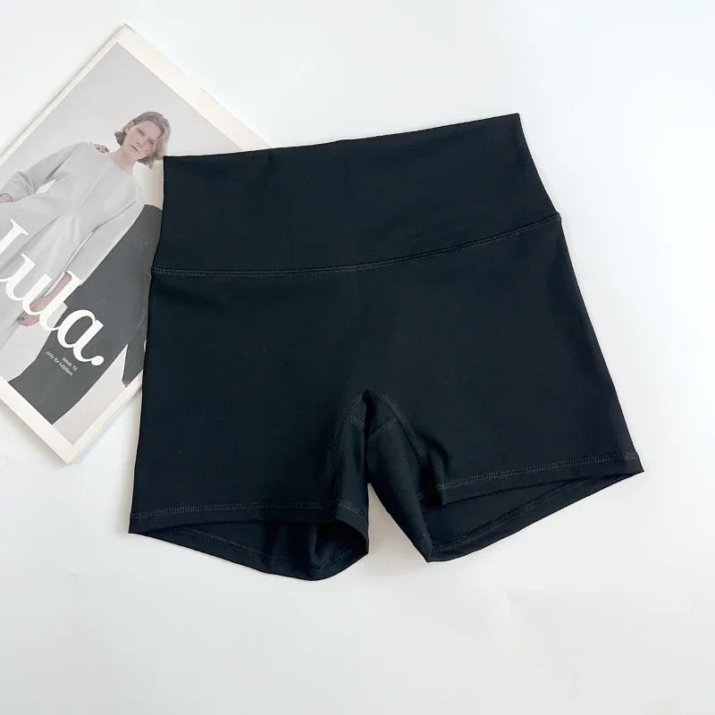 Black athletic shorts on a white background with a magazine partially visible.