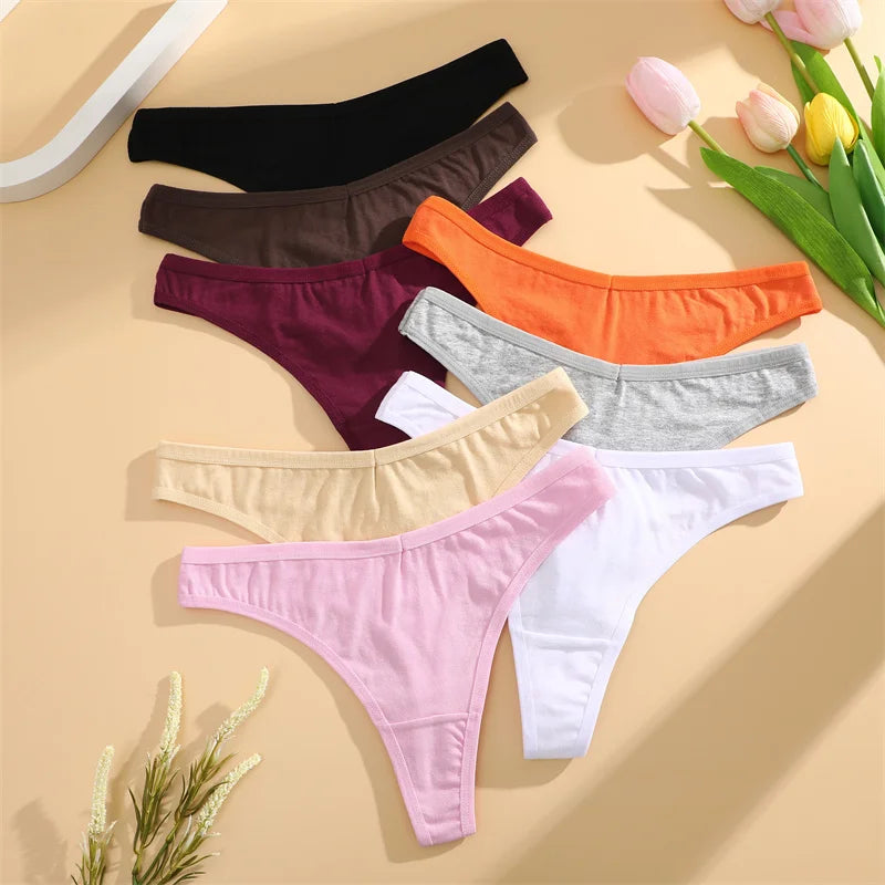 Set of colorful women's underwear on a beige surface with flowers.