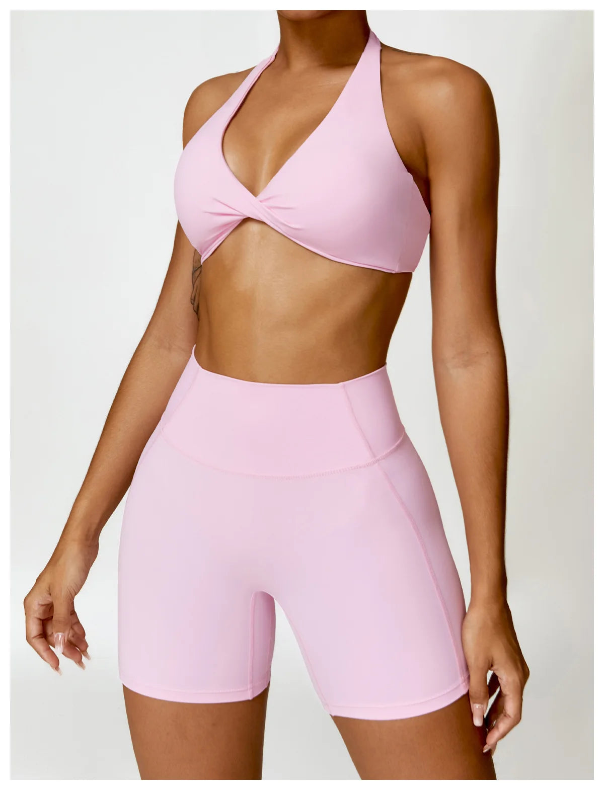 Person wearing a pink sports bra and shorts set on a white background