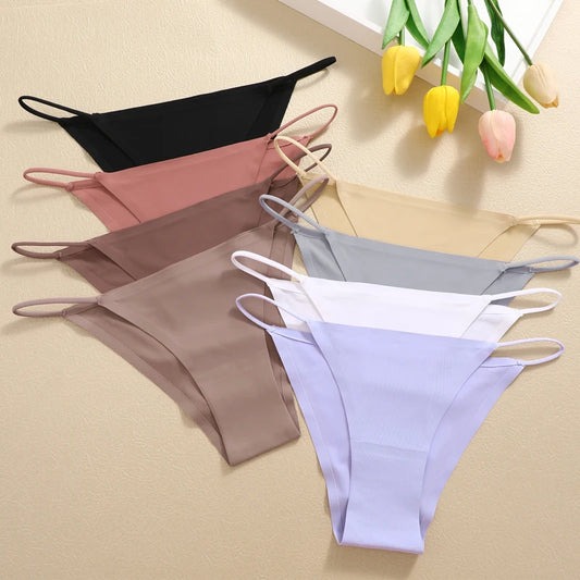 Set of women's underwear in various colors on a beige surface with tulips in the background.