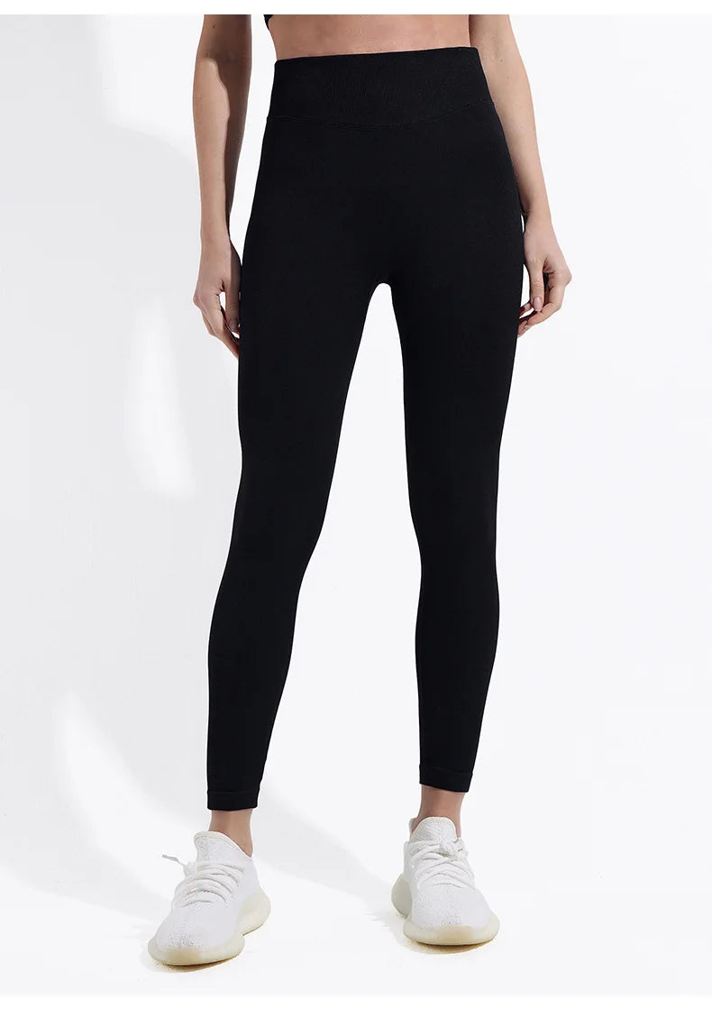 Person wearing black leggings and white sneakers on a white background
