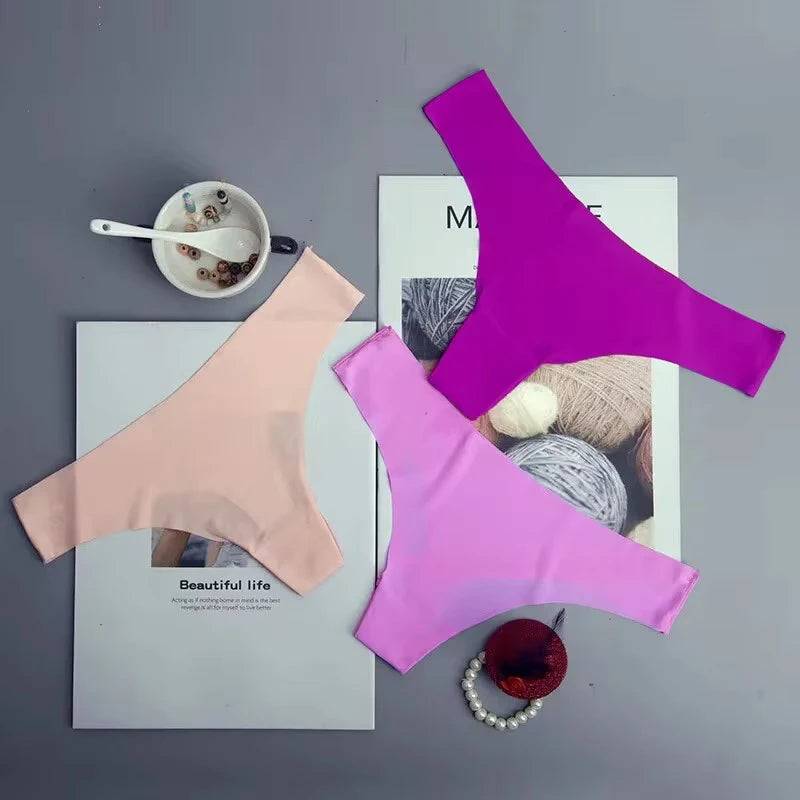 Purple and pink bras on a magazine with a cup and yarn ball on a gray surface