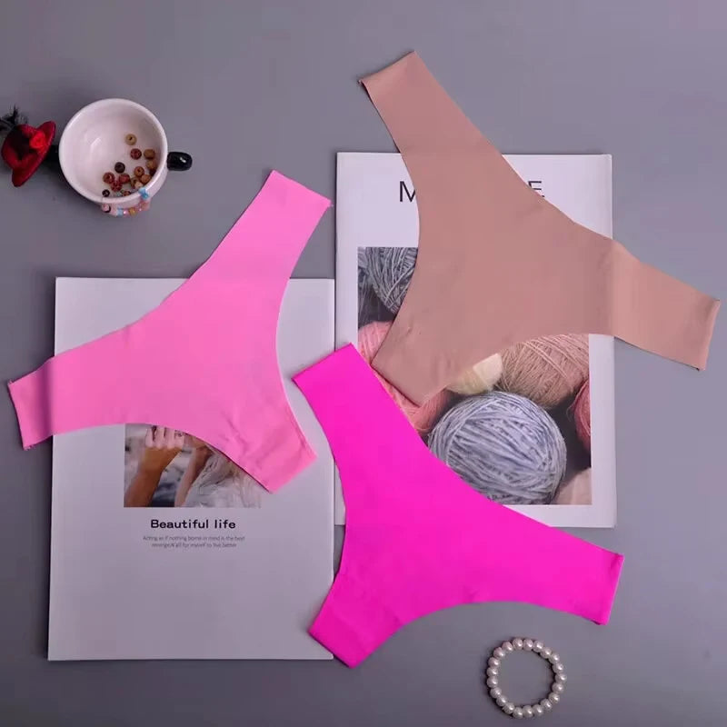 Pink and beige bralettes on a magazine with yarn and a cup in the background