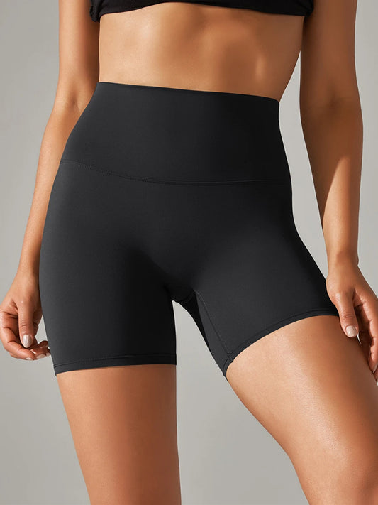 Black high-waisted shorts worn by a person on a gray background