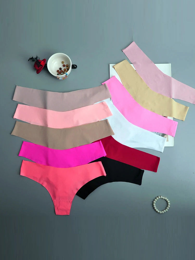 Stack of colorful underwear on a gray surface with a small bowl and flower decoration.